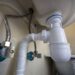 Close-up of plumbing pipes under sink.