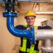 Worker in hard hat beside industrial pipes